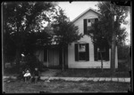 [Kansas] Photograph of children sitting outside a two-story home