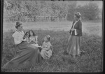 [Kansas] Photograph of woman sitting, reading a book to two girls