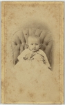 Small child in white dress resting on a cushioned chair, front