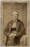 Man seated with legs crossed and one arm resting on table, front by Tyler