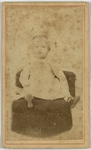 Baby in white dress sitting in black chair, front
