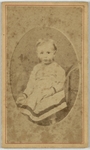 Child in white dress, sitting in a cushioned chair, front