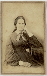 Woman in dark dress sitting, leaning on elbow, front