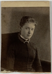 Young woman with a pony tail, sitting in a stuffed chair, front