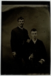 Man with mustache standing next to man sitting, front
