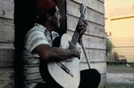 Man playing guitar outside a home 01