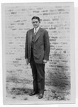 [People] Photograph of unidentified man in dark suit in front of brick wall