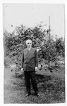 [People] Photograph of unidentified man in dark suit in front of citrus tree