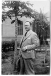 [People] Photograph of unidentified man in dark suit in front of papaya tree